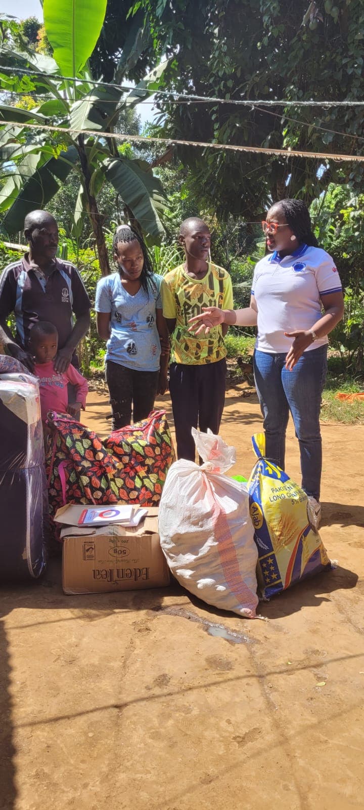 An NCHI team member speaking with a family beside donated food and household supplies