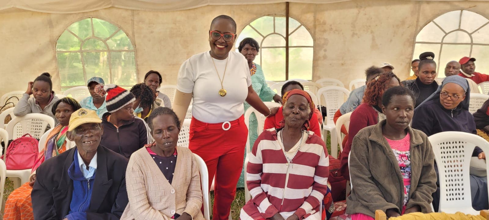 Patients and caregivers seated together at an NCHI community gathering under a tent